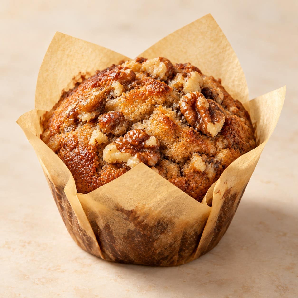 A banana walnut muffin in a tulip paper case, topped with toasted walnuts
