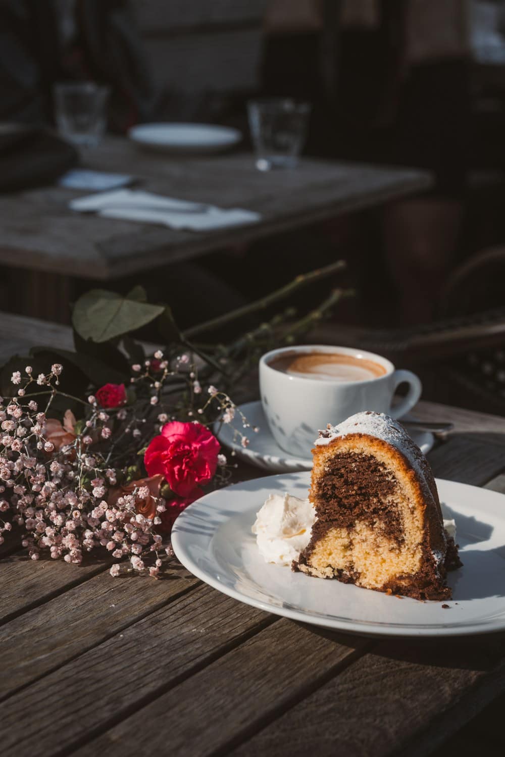 A slice of marble cake with coffee and flowers on a dark table