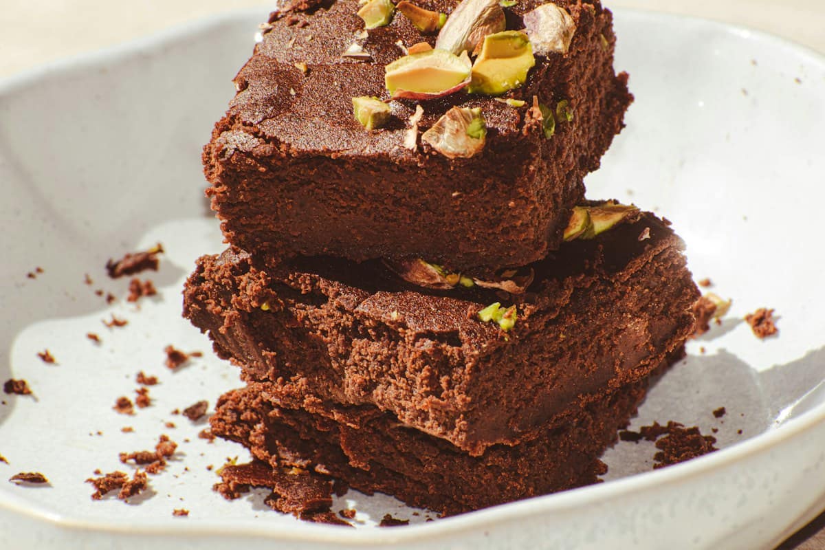 A stack of brownies topped with pistachios