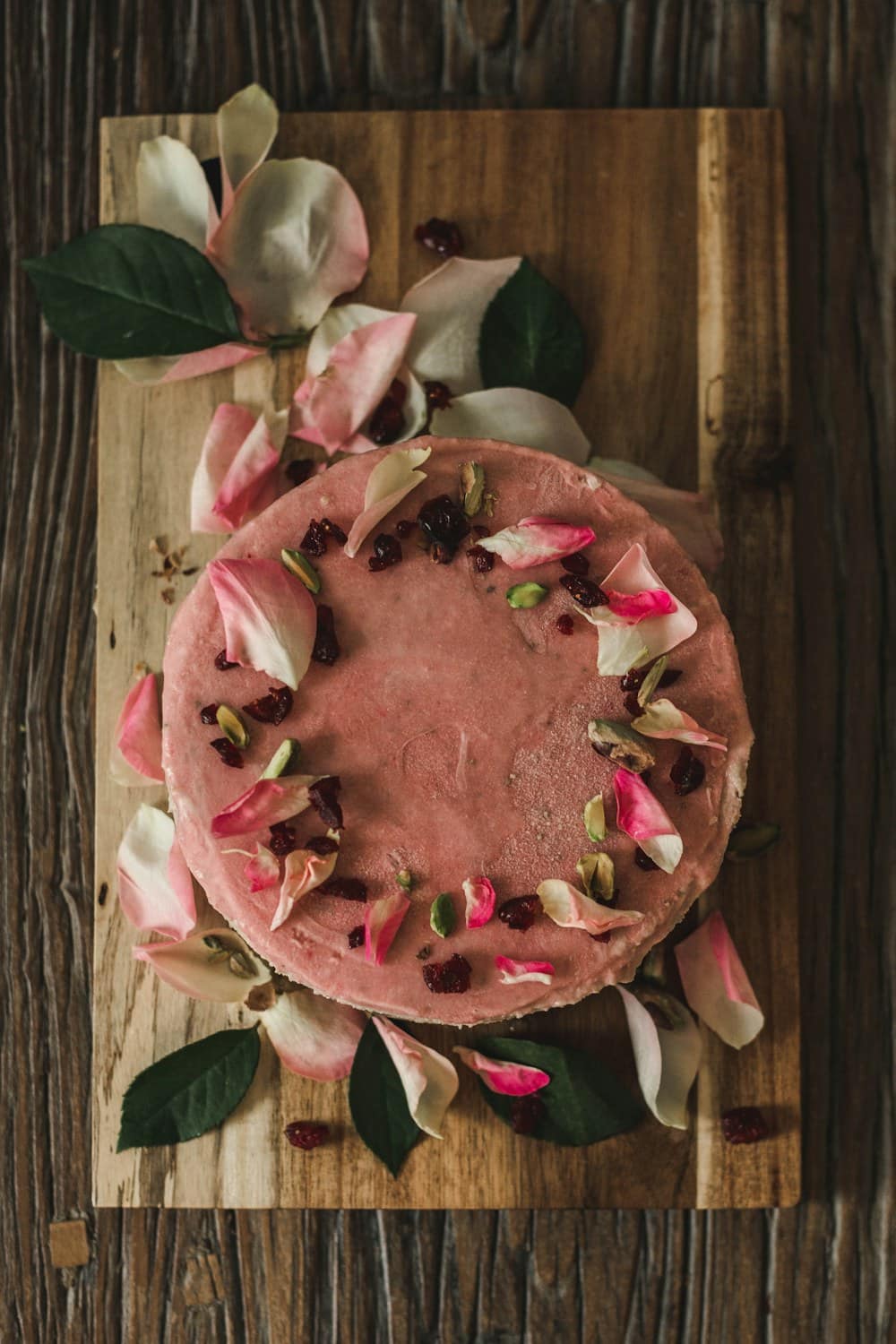 A rose-topped cake on a wooden board, from above